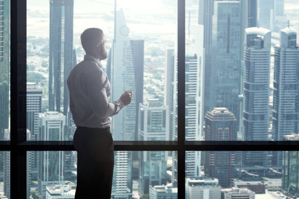 istock Businessman Drinking Coffee And Looking At City Skyline 920982180