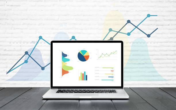 istock Laptop on wooden table showing charts and graph colourful graphics background 920998222