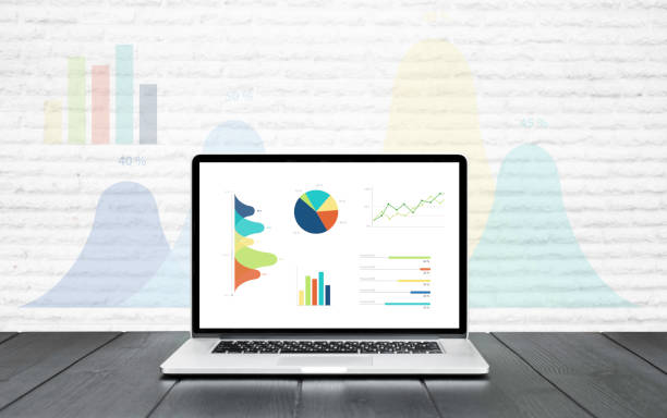 istock Laptop on wooden table showing charts and graph colorful graphics background 920998248
