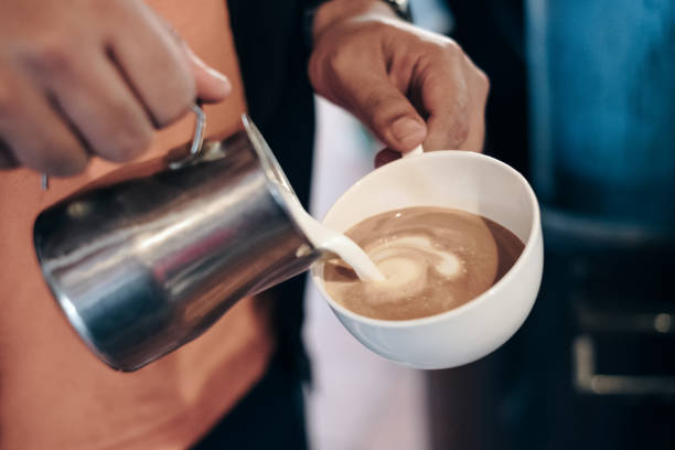 バリスタが心を作るコーヒー カップに牛乳を注いで - barista coffee coffee crop heart shape ストックフォトと画像