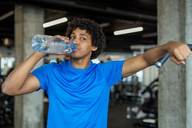 istock Handsome young man drinking water at the gym 921007716