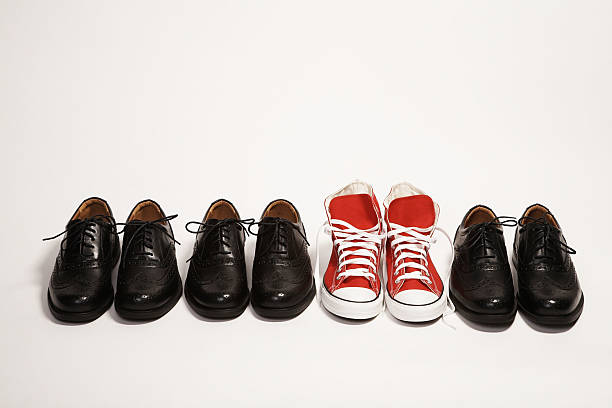 par de red zapatillas en una fila de vestido negro zapatos - contrasts fotografías e imágenes de stock