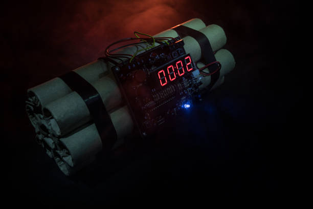 Image of a time bomb against dark background. Timer counting down to detonation illuminated in a shaft light shining through the darkness Image of a time bomb against dark background. Timer counting down to detonation illuminated in a shaft light shining through the darkness, conceptual image sabotage photos stock pictures, royalty-free photos & images