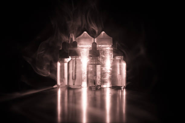 istock Vape concept. Smoke clouds and vape liquid bottles on dark background. Light effects 921012894