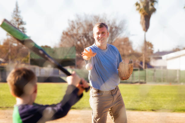 istock Mature father practicing baseball with young son ball throw 921013154