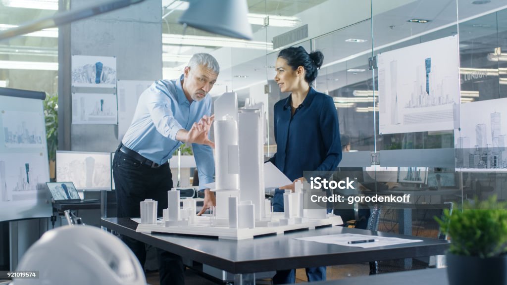 Chief Male Architect and Female Engineer Work with City Buildings Model. Bright People Work as Urban Planners. Architect Stock Photo