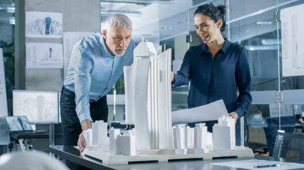 istock In the Architectural Bureau Two Professional Engineers Work on a Model of a City District. Urban Planners Work on a Functional Building Model. 921019584