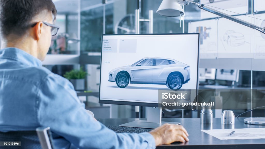 Engenheiro automotivo funciona no computador pessoal, ele aperfeiçoa o novo modelo de carro protótipo Sketch. Ele trabalha no escritório moderno e brilhante. - Foto de stock de Carro royalty-free