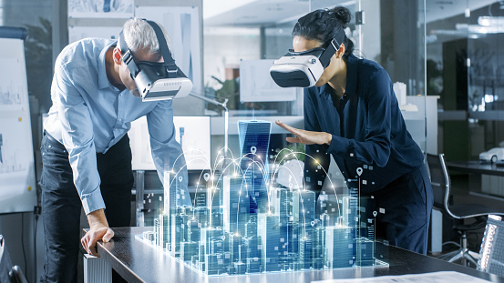 Arquitectos de machos y hembras con habían aumentada realidad auriculares Trabajo con modelo 3D de la ciudad. Gente profesional de oficina de alta tecnología utiliza aplicación de Software de modelado de realidad Virtual. photo