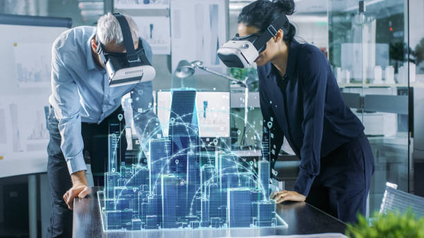 istock Male and Female Architects Wearing  Augmented Reality Headsets Work with 3D City Model. High Tech Office Professional People Use Virtual Reality Modeling Software Application. 921019712