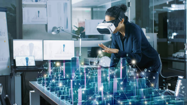 istock Professional Female Architect Wearing Makes Gestures with Augmented Reality Headset, Shows Statistics for 3D City Model. High Tech Office Use Virtual Reality Modeling Software Application. 921019714