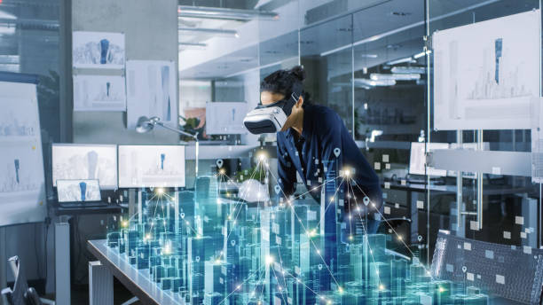 istock Professional Female Architect Wearing Makes Gestures with Augmented Reality Headset, Shows Statistics for 3D City Model. High Tech Office Use Virtual Reality Modeling Software Application. 921019722