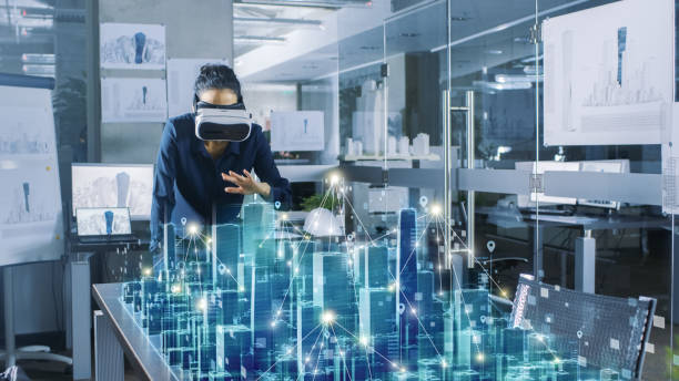 istock Professional Female Architect Wearing  Augmented Reality Headset Work with 3D City Model. High Tech Office Use Virtual Reality Modeling Software Application. 921019736