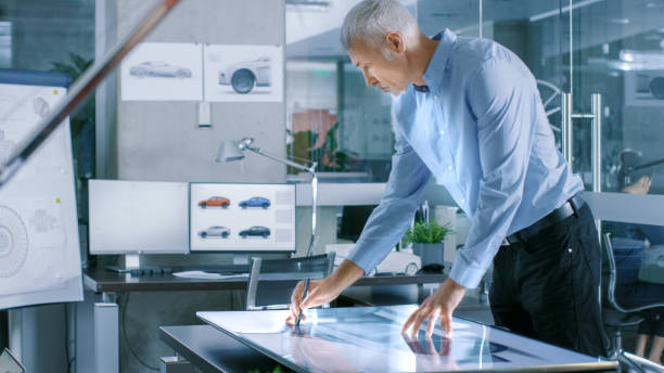 istock Experienced Automotive Designer Works With Digital Display Graphics Tablet Touschreen Table, Drawing Sketch of a New Car Prototype. 921019814