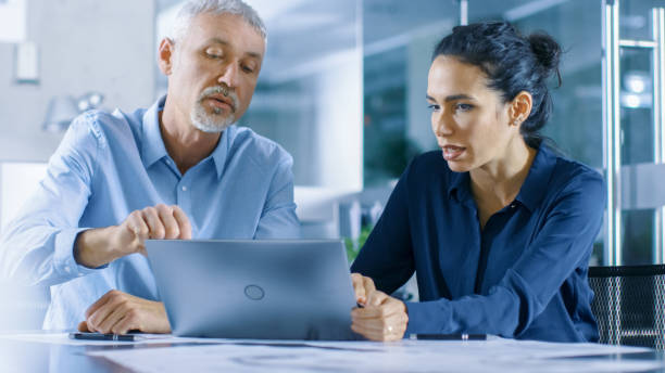 istock Experienced Male and Female Office Workers Discuss ongoing Project while Working on a Laptop. 921020082