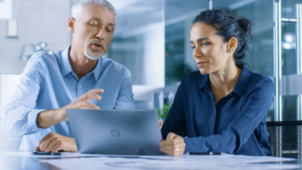 istock Experienced Male and Female Office Workers Discuss ongoing Project while Working on a Laptop. 921020092