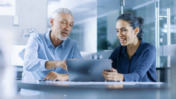 istock Experienced Male and Female Office Workers Discuss ongoing Project while Working on a Laptop. 921020104