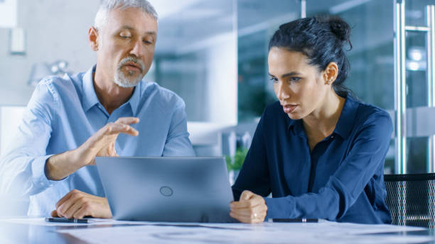 istock Experienced Male and Female Office Workers Discuss ongoing Project while Working on a Laptop. 921020106
