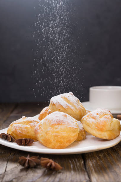 istock Delicious eclairs sprinkled with icing sugar, stand on a wooden table. Copy spase. 921022984
