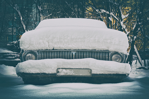 Old soviet car buried in snow on the Moscow street after a great snow storm with a vignette