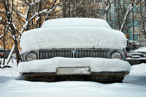 Old soviet car buried in snow on the Moscow street after a great snow storm