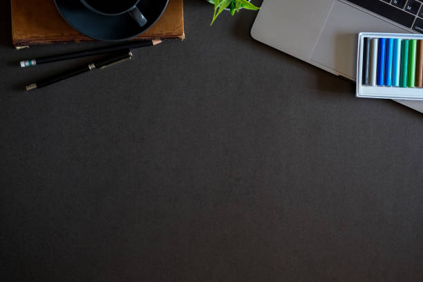 istock Designer workspace top view with essential elements on dark wooden board. 921036316