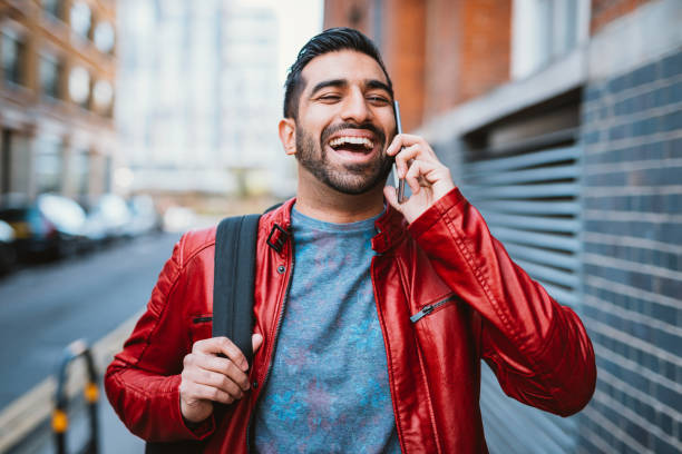 l'uomo sta usando il cellulare per parlare con gli amici - multi tasking asian and indian ethnicities asian ethnicity lifestyles foto e immagini stock