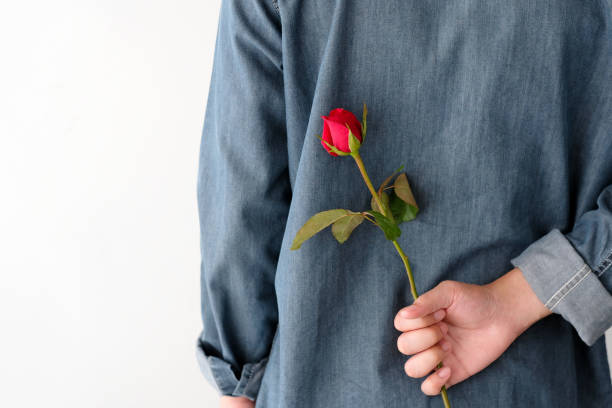 istock Valentine concept, Man holding red rose hiding on back on white background 921039630