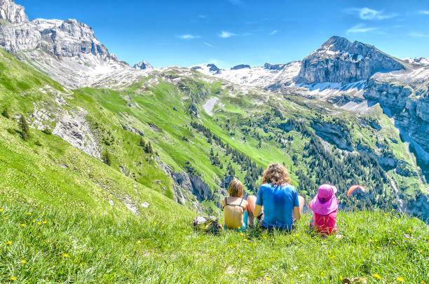 молодые люди, сидящие на лугу в окружении швейцарской природы - austria summer european alps mountain стоковые фото и изображения