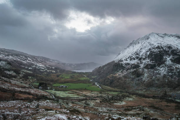 Beautiful Winter landscape image in Llyn Gwynant in Snowdonia National Park with snow capped mountains in background Beautiful landscape image in Winter of Llyn Gwynant in Snowdonia National Park with snow capped mountains in background llyn gwynant stock pictures, royalty-free photos & images