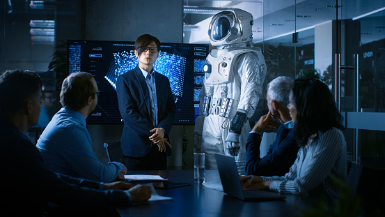 In the Conference Room of the Center of Technology Chief Engineer Presents Next Generation Space Suit to a Board of Directors. Completely Original Design with Integrated AI and Neural Network Systems.