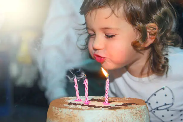 Photo of The girl puts out the candles on a birthday cake