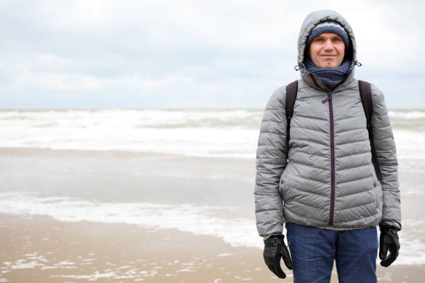 Mature tourist in jacket against the surf of the North Sea in winter
