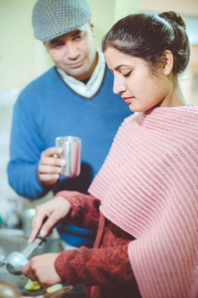 istock Young woman working in kitchen and husband helping her. 921092644