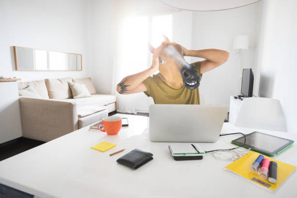 istock Man with horse head mask working at home 921095628