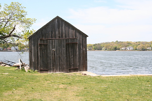 Old Shack on the water with large homes in the background