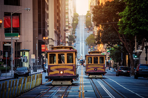 Classic view of historic traditional Cable Cars riding on famous California Street in beautiful early morning light at sunrise in summer with retro vintage style cross processing filter effect, San Francisco, California, USA
