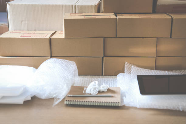 istock notebook, packing accessories at workplace of startup small business owner. cardboard parcel box for online selling. entrepreneur seller desk. e-commerce, shipping concept 921112752