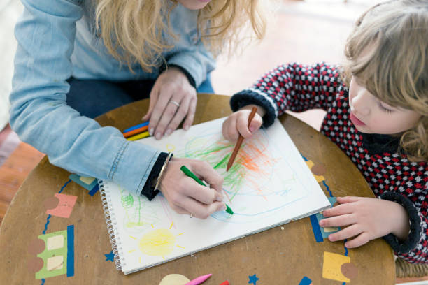 istock Woman and child drawing with crayons 921145520