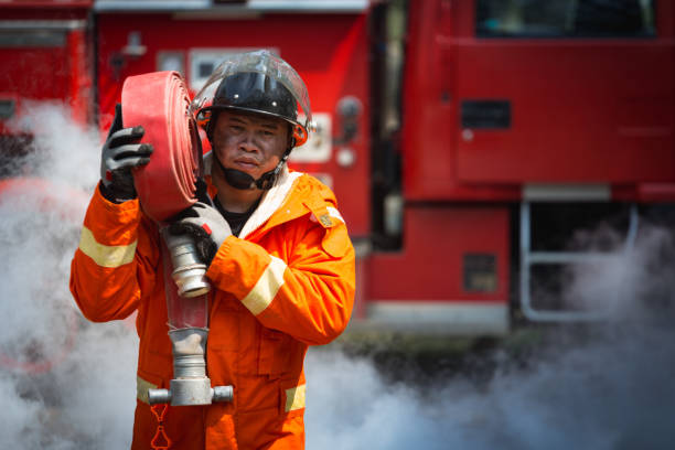 istock Firefighters training, Team practice to fighting with fire in emergency situation. A fireman carry a water hose run through flame 921145700