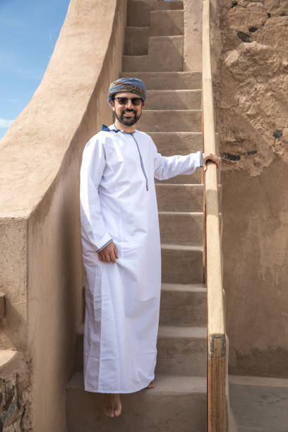 uomo arabo in abito tradizionale omani a piedi giù per le scale - ghoutra foto e immagini stock