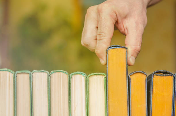 a man's hand pulls a book out of the shelf