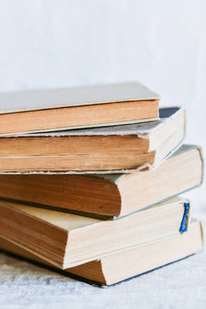 istock a stack of old battered books, and upstairs, an open book on a white background, copyspace 921147762