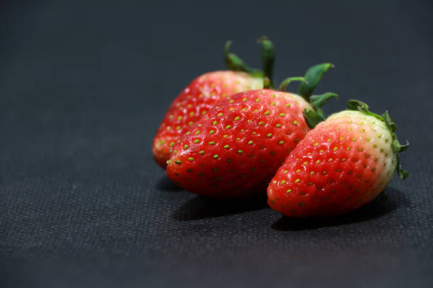 istock Three Strawberry on the black floor. 921152910