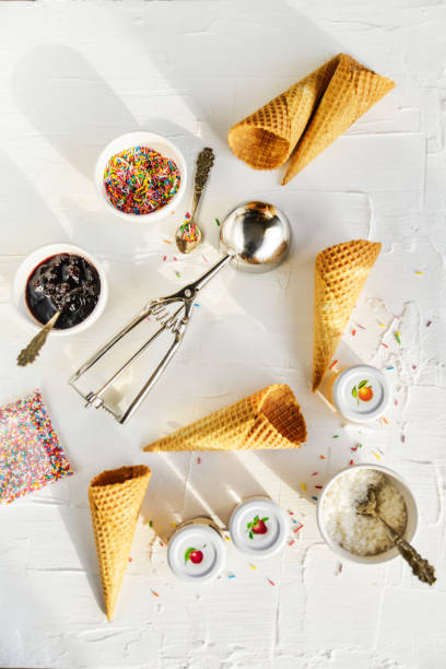 a kit for making ice cream on a white background, Flatley, top view: ice cream spoon, ice cream cones, jam, topping, chocolate, sprinkles, coconut