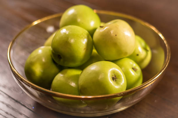 green apples on wooden table in clear bowl