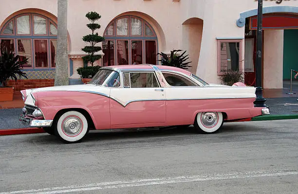 Photo of Vintage pink and white car parked on street