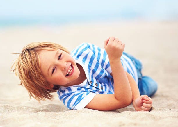 istock cute happy laughing boy, kid having fun on sandy beach, summer vacation 921196108