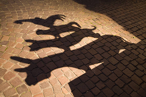 Shadows of town musicians against a cobblestoned path stock photo