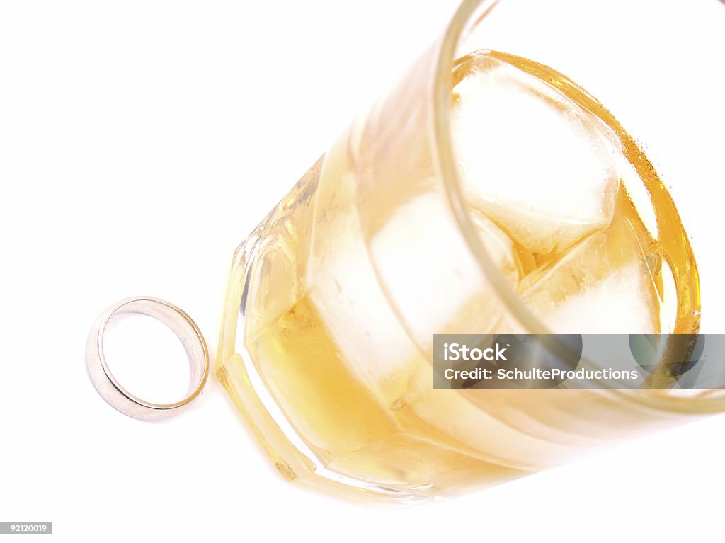Marriage & Alcohol a glass of hard liquor and a wedding ring isolated on white. Concept and Idea. Alcohol - Drink Stock Photo